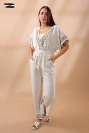 Woman wearing a white outfit with embroidery on a beige background